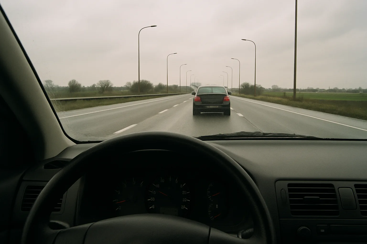 View from inside the car on a Belgian motorway, a car ahead at a safe distance.
